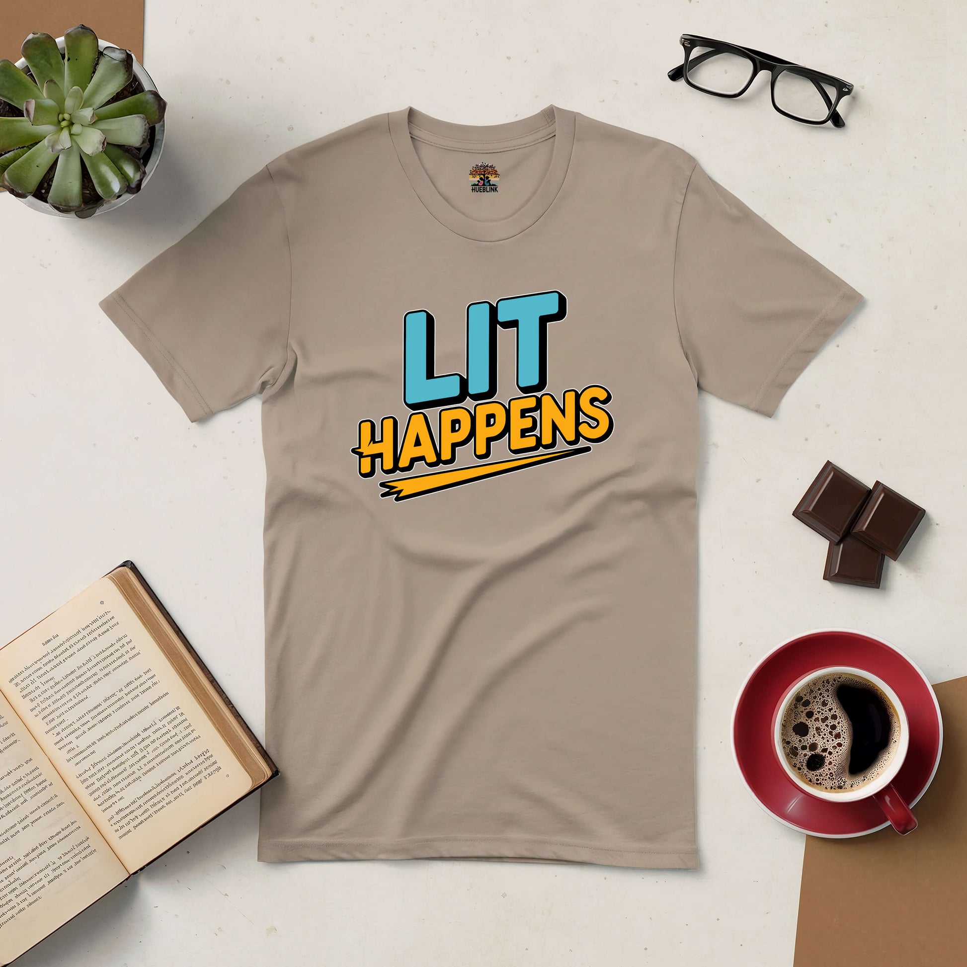 "Lit Happens Tee for book lovers with coffee, chocolate, glasses, succulent, and open book on desk"