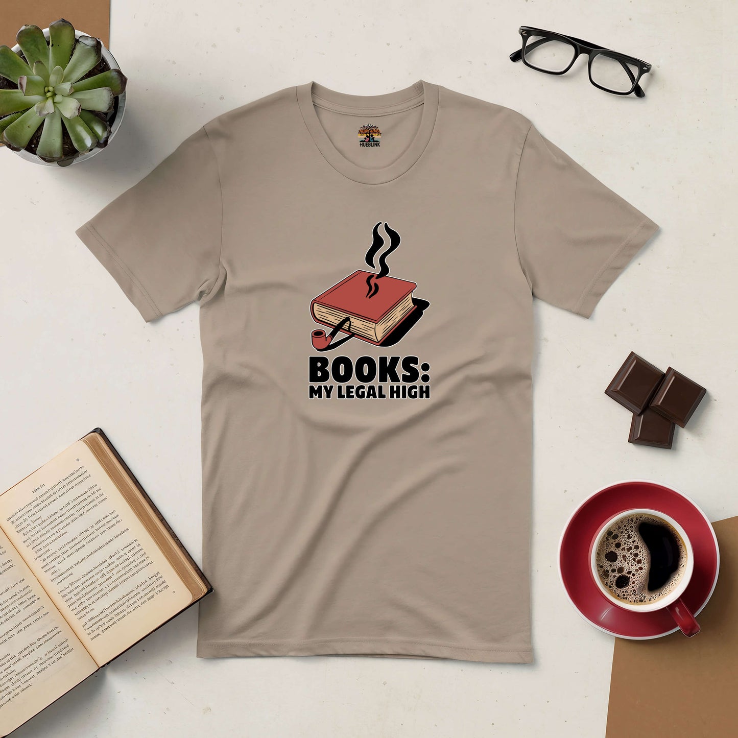 "Books: My Legal High tee with book design, coffee cup, eyeglasses, chocolate, and plant on a table"