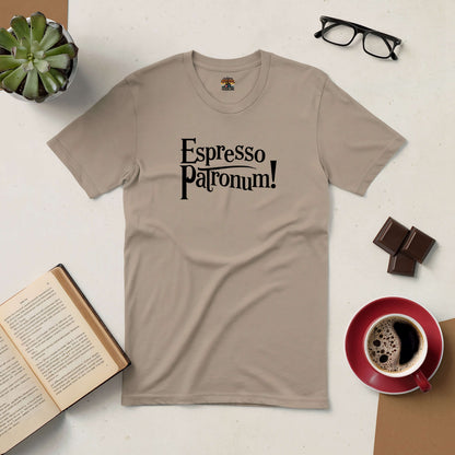 Beige "Espresso Patronum!" t-shirt on table with coffee, book, glasses, plant, and chocolate, perfect for coffee lovers and wizards.