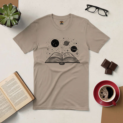 Beige t-shirt with book and planets design, showcasing the Journey Through Space Tee surrounded by coffee, glasses, and a book.