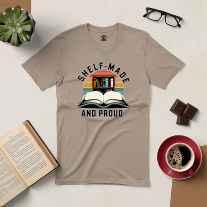 "Shelf-Made And Proud Tee with book-themed design, displayed with coffee, chocolate, and open book on a table, perfect for book lovers"