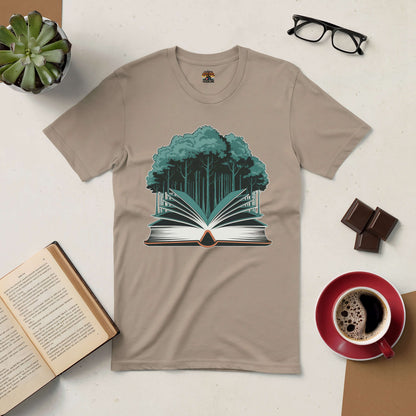 Beige tee with forest and book graphic, Rooted in Story design, surrounded by coffee, glasses, succulent, chocolate, and open book.