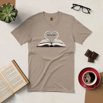 Beige "Reading Is My Cardio" tee with book graphic, surrounded by coffee, chocolate, open book, glasses, and plant. Perfect for book lovers.