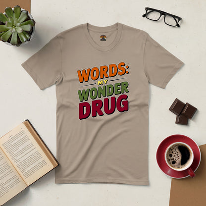 Beige Word Therapy Tee with "Words: My Wonder Drug" text, surrounded by a book, coffee, glasses, plant, and chocolate.