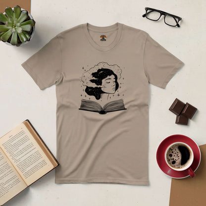 Beige Universal Consciousness Tee with ethereal design, depicting a woman's head merging with stars and a book, beside coffee and glasses.