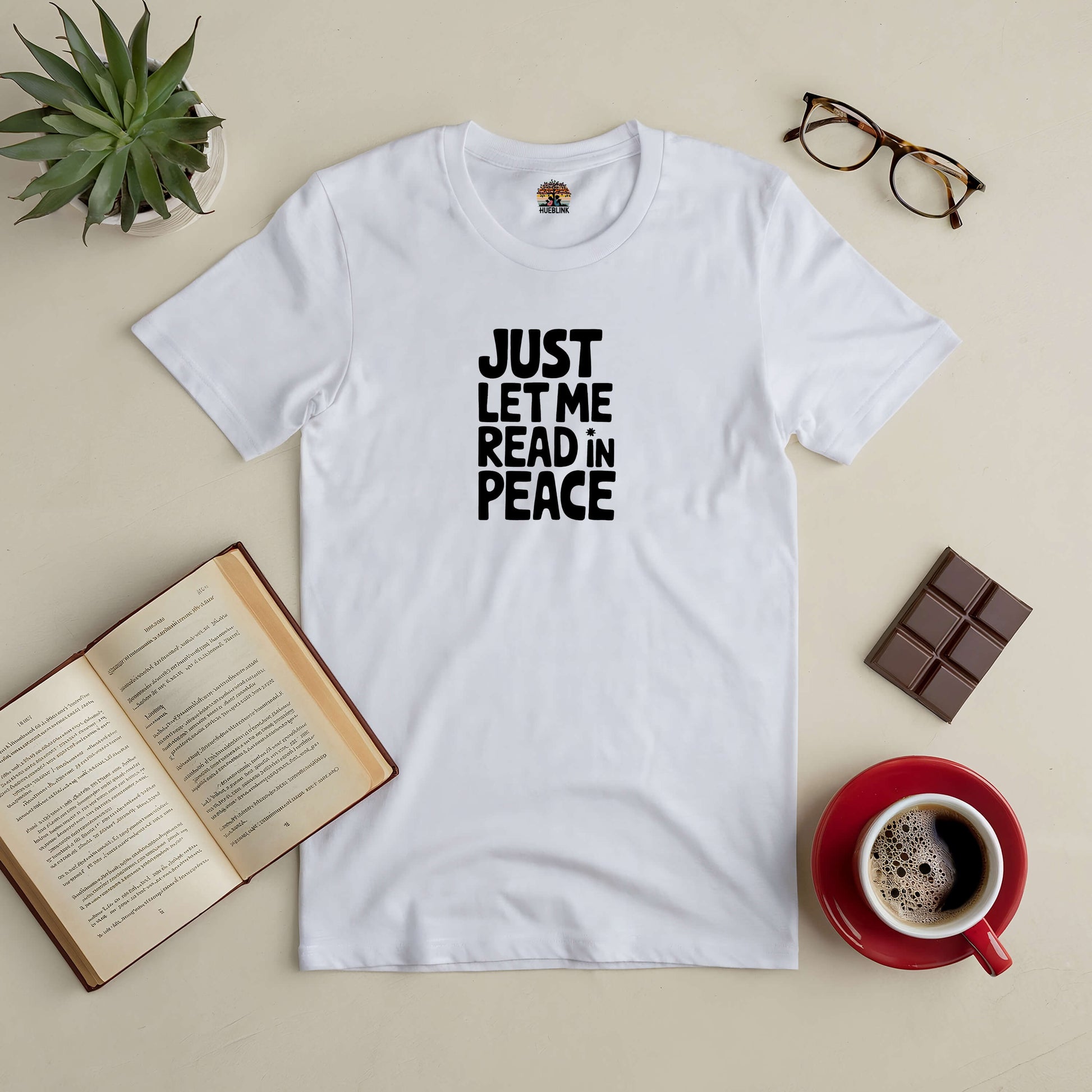 White "Just Let Me Read in Peace" tee with an open book, glasses, chocolate, and coffee, perfect for avid readers seeking solitude.