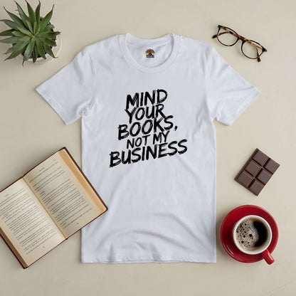 "Mind Your Books, Not My Business Tee with open book, glasses, chocolate, and coffee on a table"