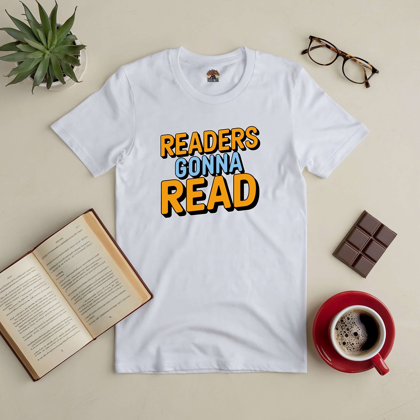 "Readers Gonna Read tee with books, glasses, coffee, and chocolate on a table"