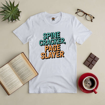 White "Spine Cracker, Page Slayer" tee for book lovers, displayed with open book, glasses, chocolate, and coffee.