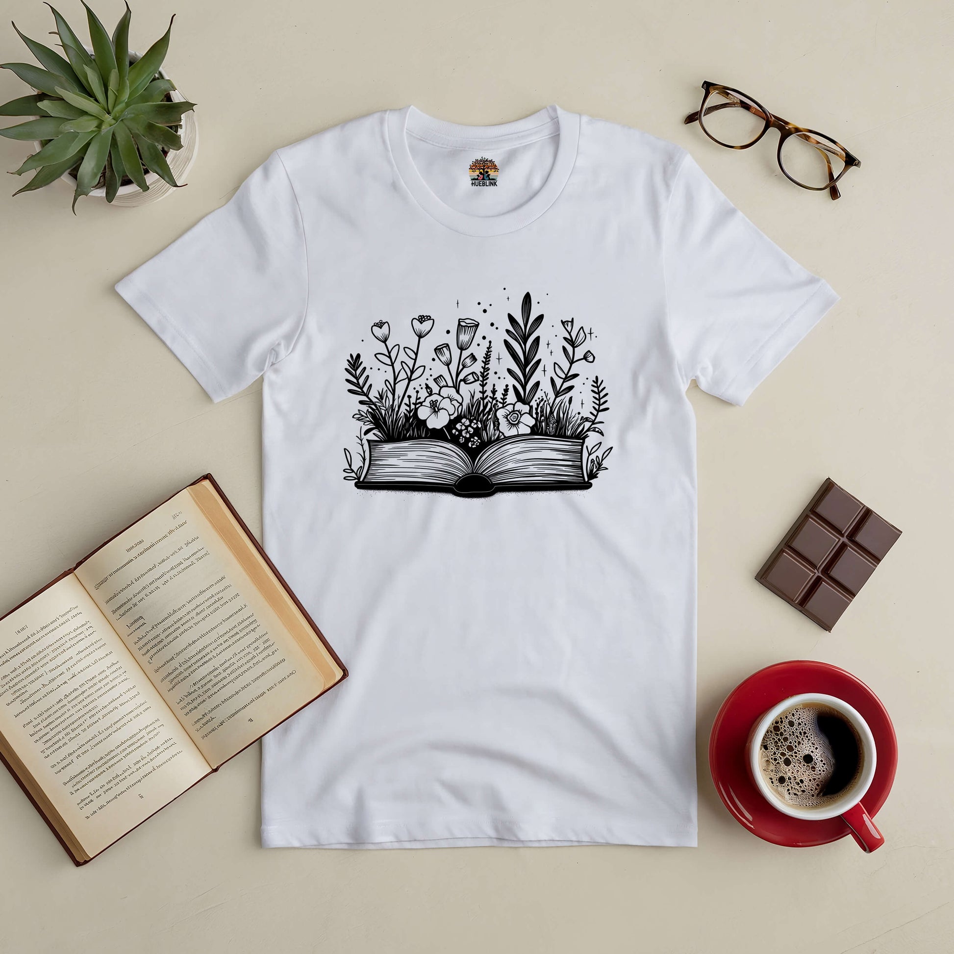 "Books and Blooms Tee with floral book design, perfect for book lovers and nature enthusiasts, styled with coffee and chocolate"