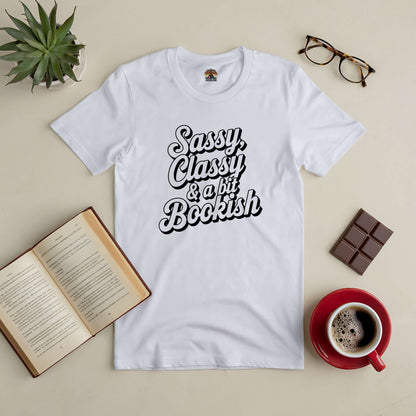 White Sassy, Classy & a Bit Bookish tee with a book, coffee, glasses, and chocolate bar on a table. Perfect for stylish book lovers.