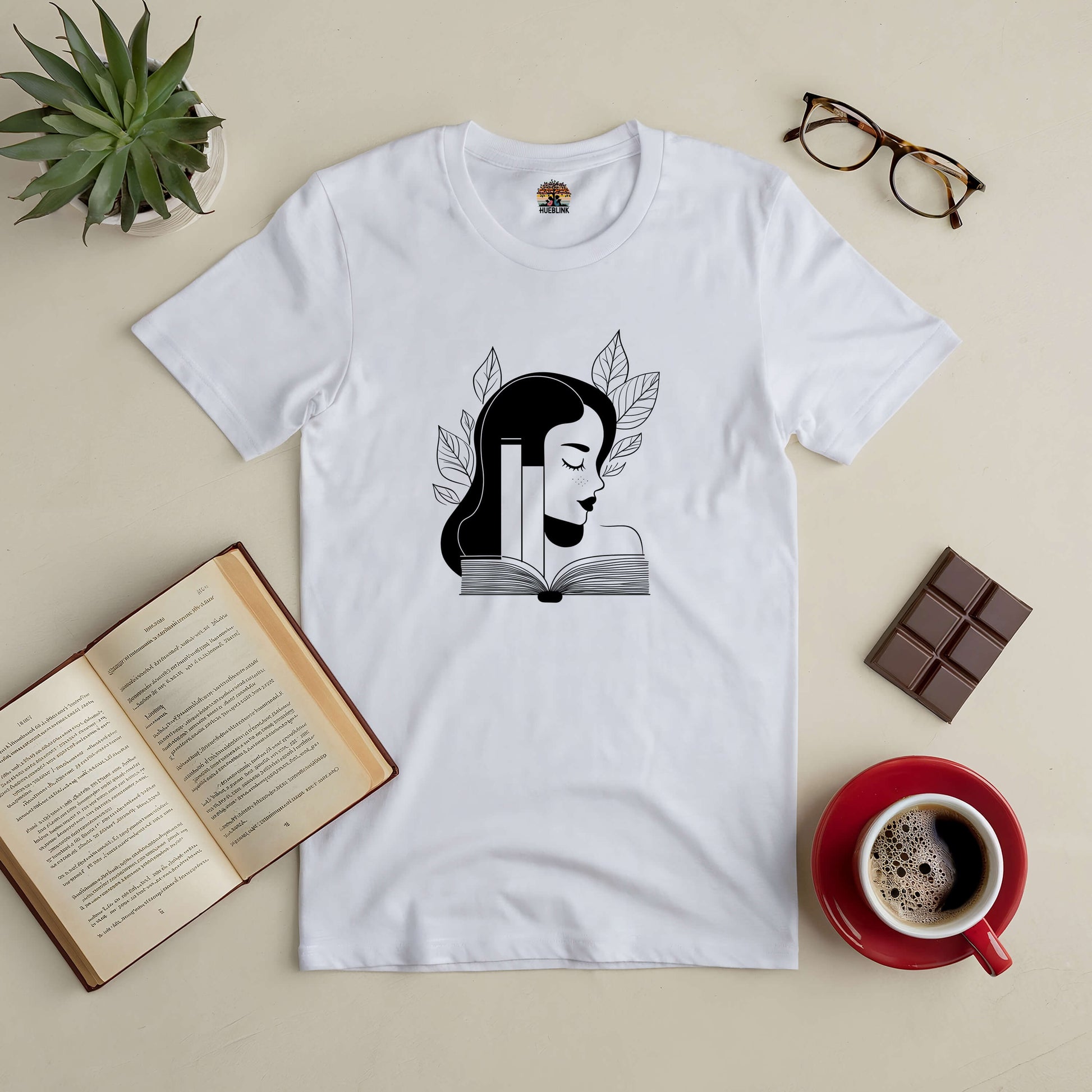 "Beauty in Every Page Tee with elegant book design for book lovers, features open book, coffee, and plant on a flat lay background."