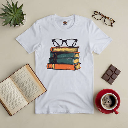 White t-shirt with vintage book stack and glasses design, styled with coffee, open book, and glasses on a table.